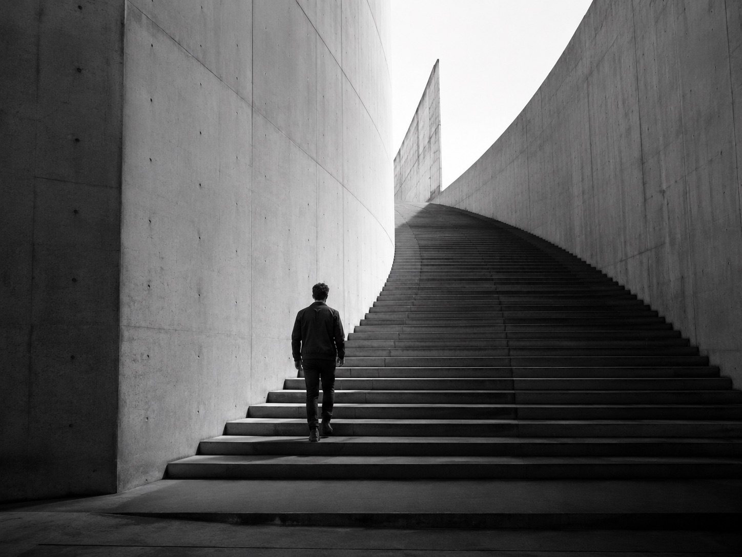 Pessoa subindo uma escadaria de concreto em curva